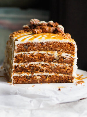A four layer carrot cake frosted with cream cheese frosting and topped with candied pecans and caramel.