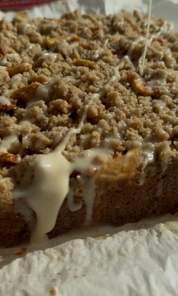 Maple glaze being drizzled over a crumb cake.