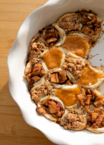 A white pie plate filled with pumpkin, pecan and apple mini hand pies.