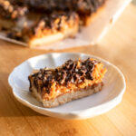 A coconut chocolate shortbread bar on a white plate.