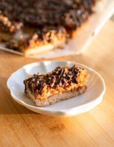 A coconut chocolate shortbread bar on a white plate.
