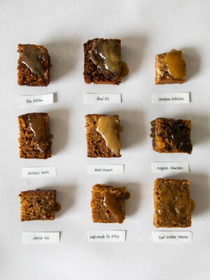 9 squares of sticky toffee pudding with sauce on a gray background.