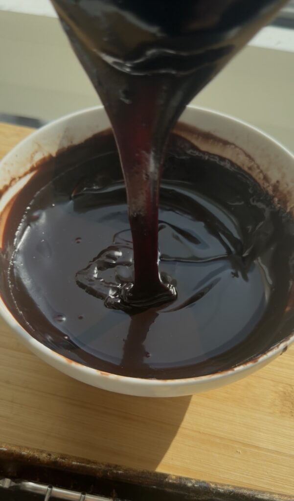 Pouring chocolate ganache into a bowl.