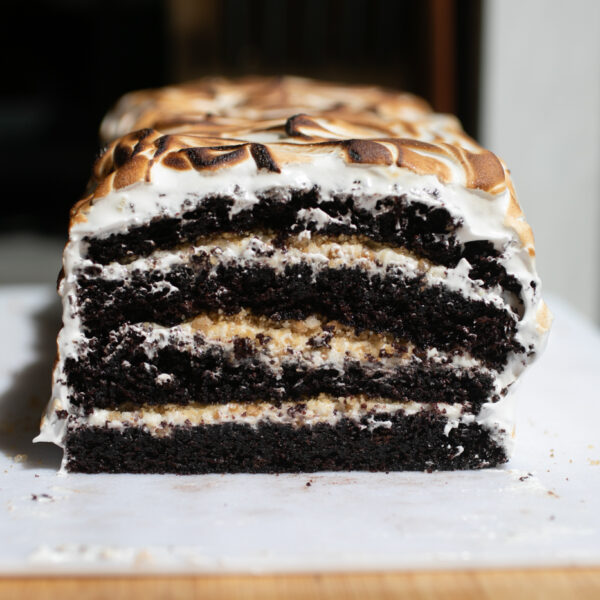 A four layer chocolate cake on a cutting board.