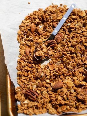 Granola spread out on a sheet of parchment with spoon.