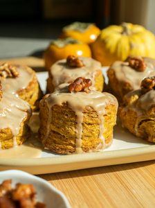 A pumpkin scone with a maple glaze on a white plate.