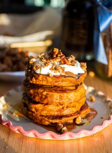 A stack of pumpkin pancakes topped with yogurt and candied walnuts.